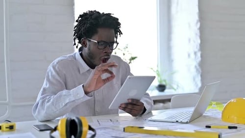 African Engineer Celebrating Success on Tablet