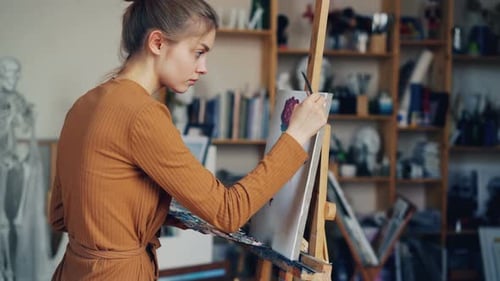 Creative Girl Is Busy Painting Flowers on Canvas Working Alone in Workshop Using Brush and Oil