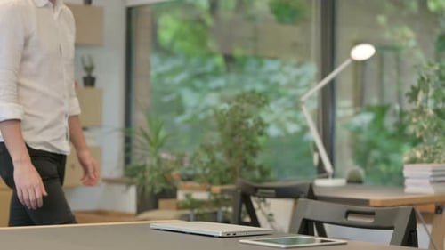 Young Man Coming and Opening Laptop Starting Work in Modern Office
