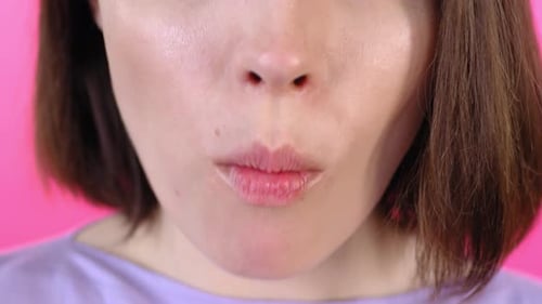 Woman Biting Into a Pink Frosted Donut
