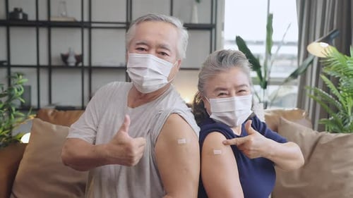 Senior Couple Showcasing Vaccine Bandages and Giving Thumbs Up