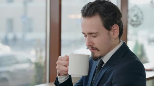 Young Businessman Drinks Coffee in Cafe
