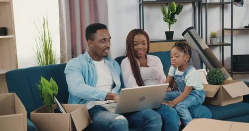 Padre afroamericano muestra un divertido Vídeo en una computadora portátil a su linda hija pequeña