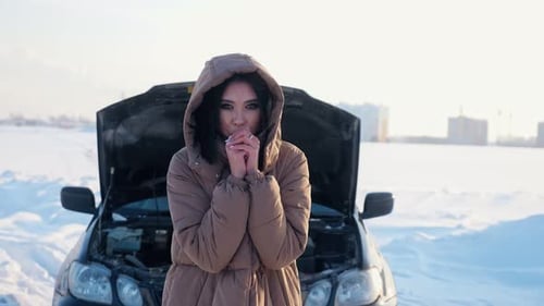 Woman Stands Near Car in Winter With Hood Open