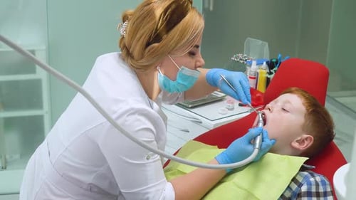 Red-haired Boy at Reception at Dentist in Dental Chair. Pediatric Dentistry