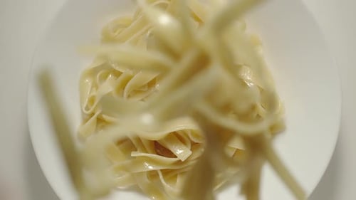 SLOW MOTION: Fettuccine Pasta Falling Into A White Plate - Top View