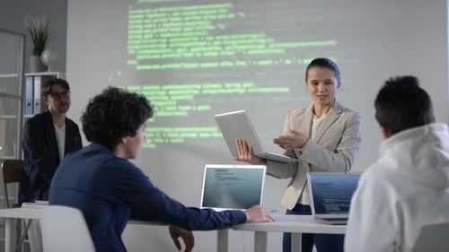 Businesswoman Presenting Computer Code to Students in Workplace