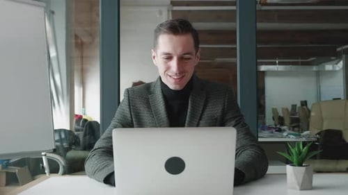 Happy Man Smiling Working on Laptop in Office