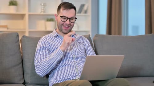 Man Chatting on Laptop While Sitting on Couch