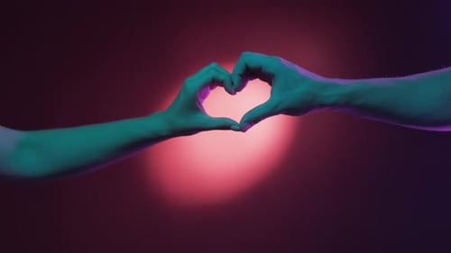 Hands Form a Heart in Pink Light