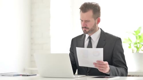 Man Working in Modern Office with Laptop and Document