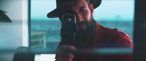 A young man aims a 35mm film Camera