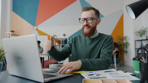Cheerful Young Businessman Enjoying Work with Laptop in Creative Modern Office