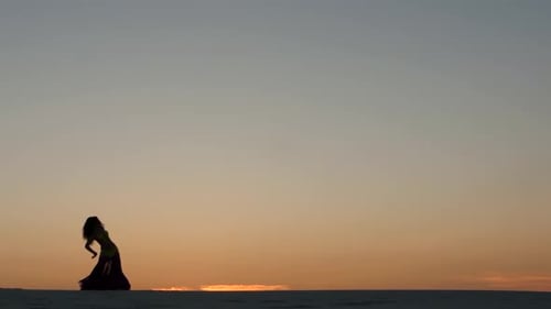 Girl Is Dancing Belly Dancing Against the Beautiful Sunset on the Beach. Silhouettes