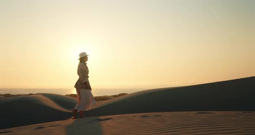 Woman Walking on Sand Dune at Sunset