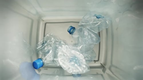 Close up video of plastic bottles falling into the garbage bin. Shot with RED helium camera in 8K.
