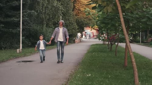 Hippie Grandfather and Boy Walking in the Park Holding Hands