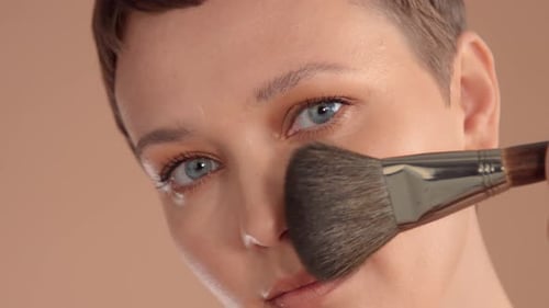 Caucasian Woman with Short Haircut and Natural Beige Makeup in Studio on Beige Background