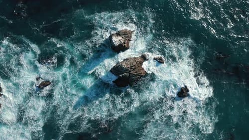 Giant Waves Crashing at Rocky Sea Cliffs with Splashing White Foam, Top Aerial