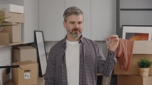 Smiling Man Holds Keys in New Home With Boxes