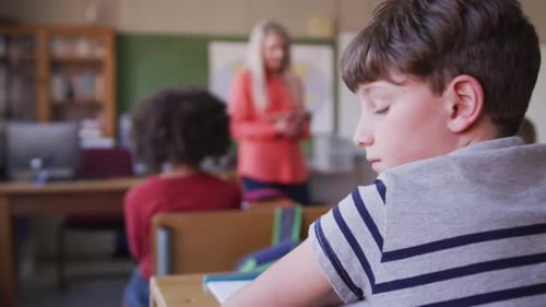 Boy smiling while sitting on his desk at school