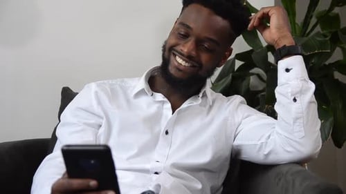 Man Relaxes Indoors Using a Mobile Phone