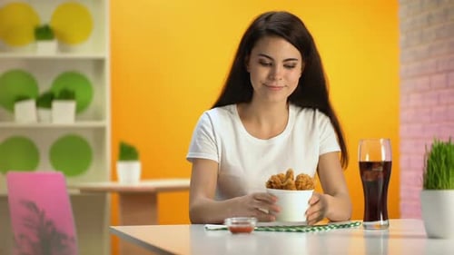 Smiling Woman Smells Fried Chicken at Table