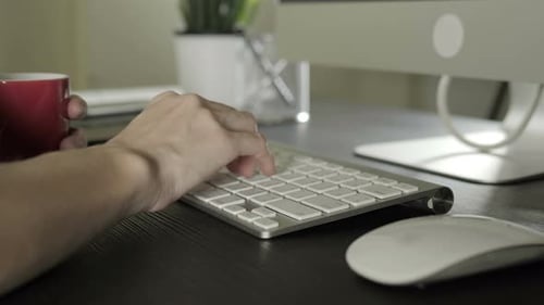 Hands Typing on Keyboard at Desk