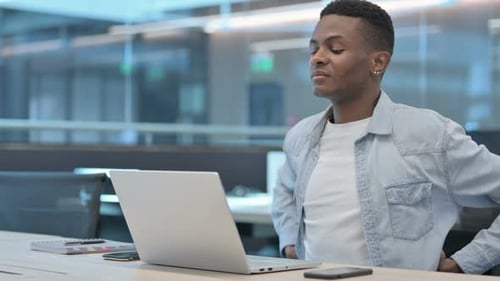 Young Adult Working on Laptop at Modern Workplace