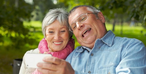 Senior Couple Enjoying Smartphone on Park Bench