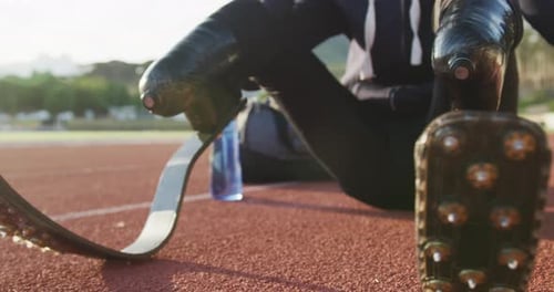 Athlete with Running Blades Sits Track, Adjusting Headphones