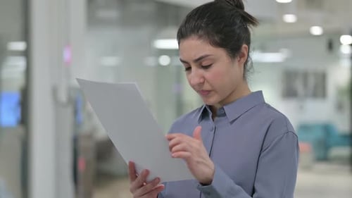 Woman Reviews Paperwork in Bright Modern Office