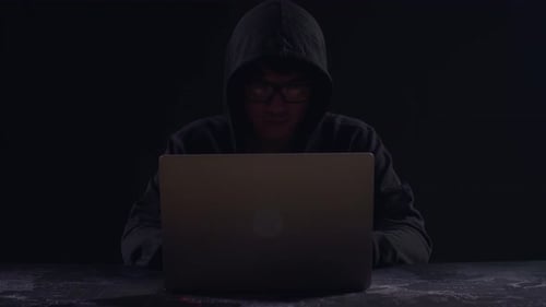 Asian Male Hacker Using Laptop Computer Hacking With Dark Background