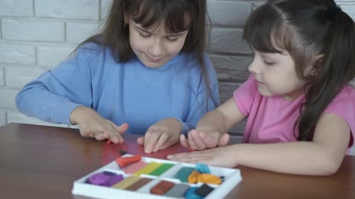Two Children Playing with Colorful Clay at Table