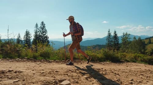 A Man with Trekking Poles Hiking in the Mountains