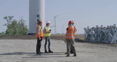 Engineers Inspecting Construction Site Near Windmill