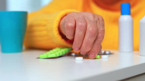 Hands Close Up Elderly Woman Taking Pill at Home in the Kitchen