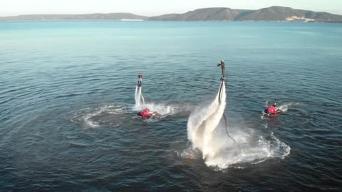 Sportliche Männer machen Tricks mit Jetpacks über Meerwasser