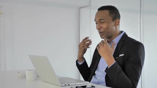Smiling Man Video Conferencing on Laptop in Office