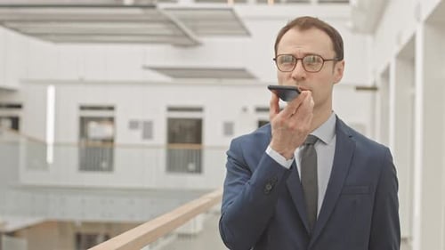 Man Dictates Message on Smartphone in Modern Office