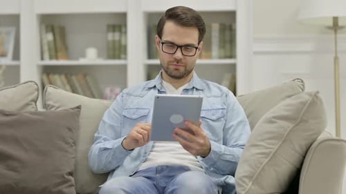 Young Adult Man Uses Tablet at Home