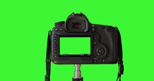 Photographer's male hand is pressing a record button. DSLD camera isolated on keyed green screen
