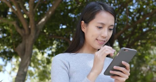 Woman Using Mobile Phone Outdoors on Sunny Day