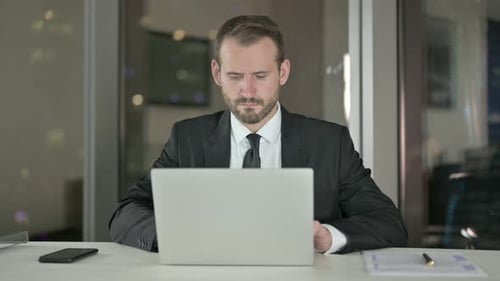 Focused Businessman Working Late at Office on Laptop