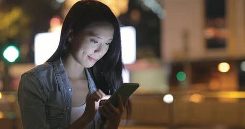 Woman using mobile phone at night
