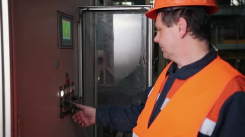 Factory Worker Adjusting Machine Control Panel