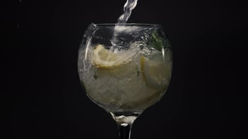 Clear Liquid Pouring into Glass with Ice and Lemon