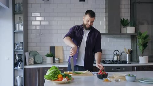 Smiling Man Cooking Vegetables in Bright Kitchen