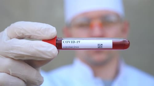 Doctor Holds Blood Sample Test Tube Labeled COVID-19