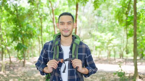 Portrait of Asian handsome male backpacker traveling in forest alone.